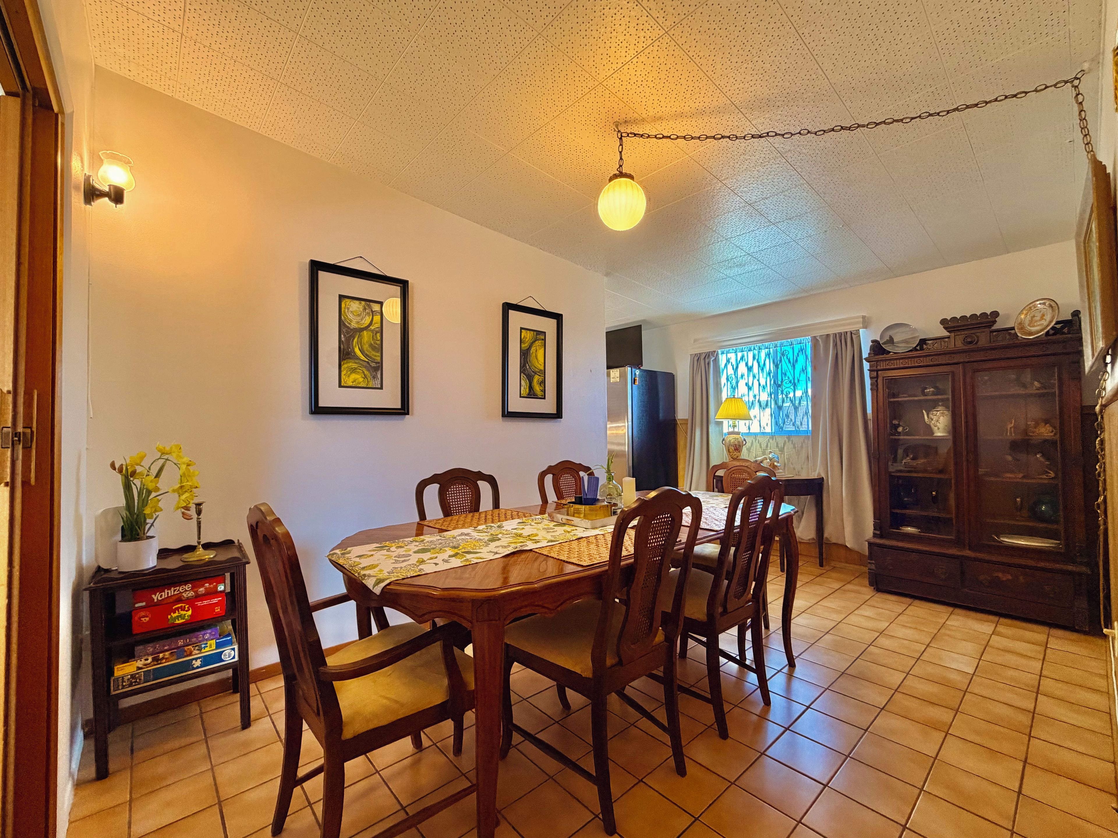 A dining area with a wooden table, chairs, and a tiled floor.