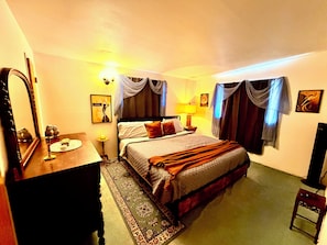 Une chambre d’hôtel avec un lit, une table de chevet, une lampe et un miroir.