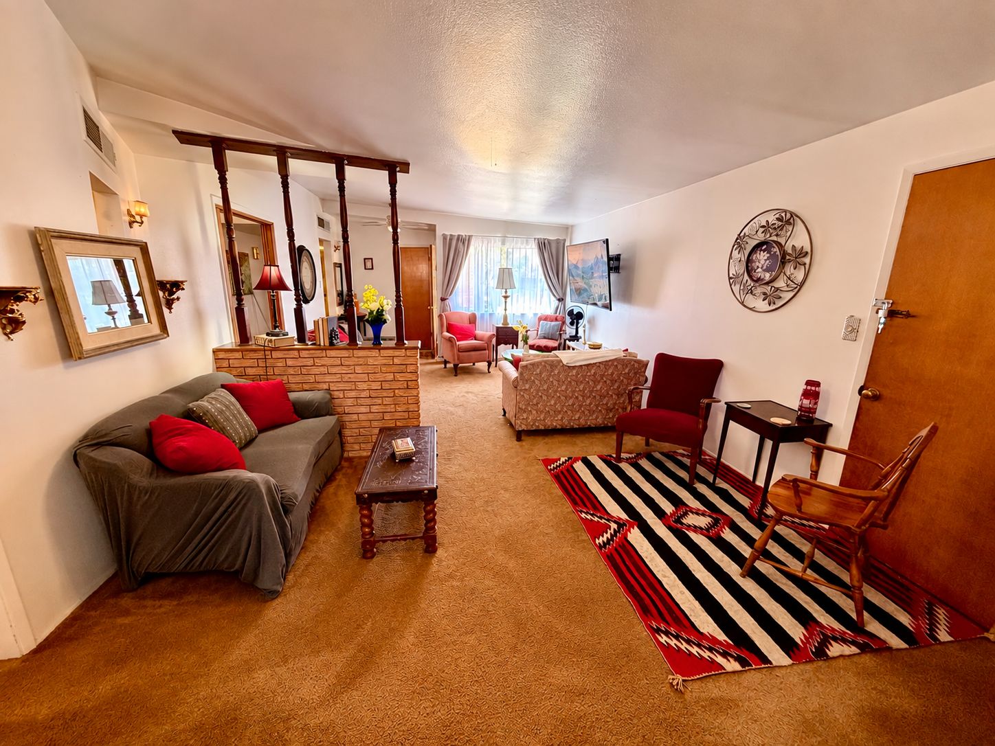 Ein Wohnzimmer mit einer Couch, einem Sessel, einem Couchtisch und einem gemusterten Teppich.