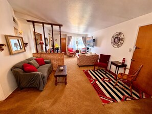 A living room with a sofa, armchair, coffee table, and a patterned rug.