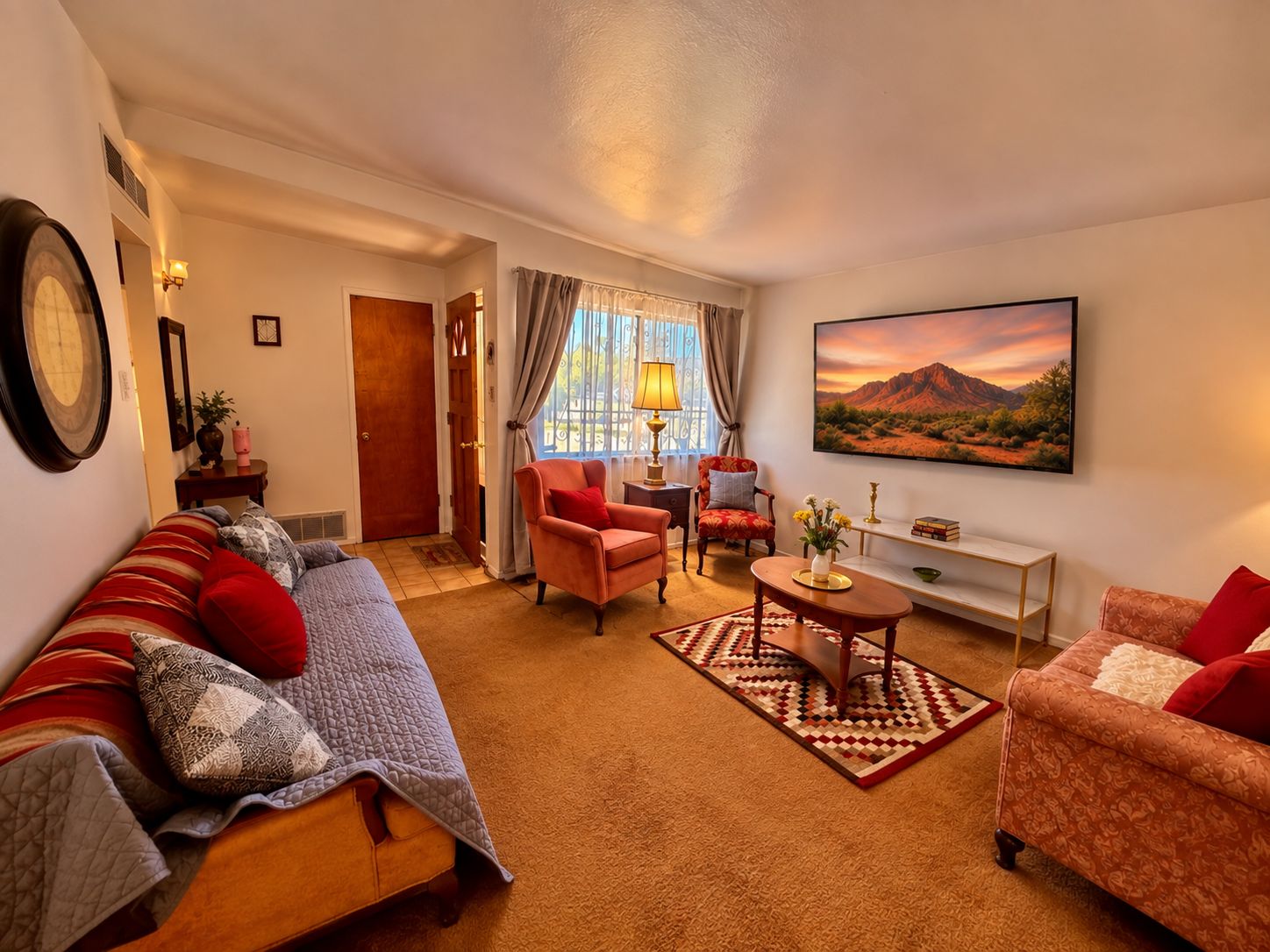 A living room with a sofa, armchairs, a coffee table, and a TV.