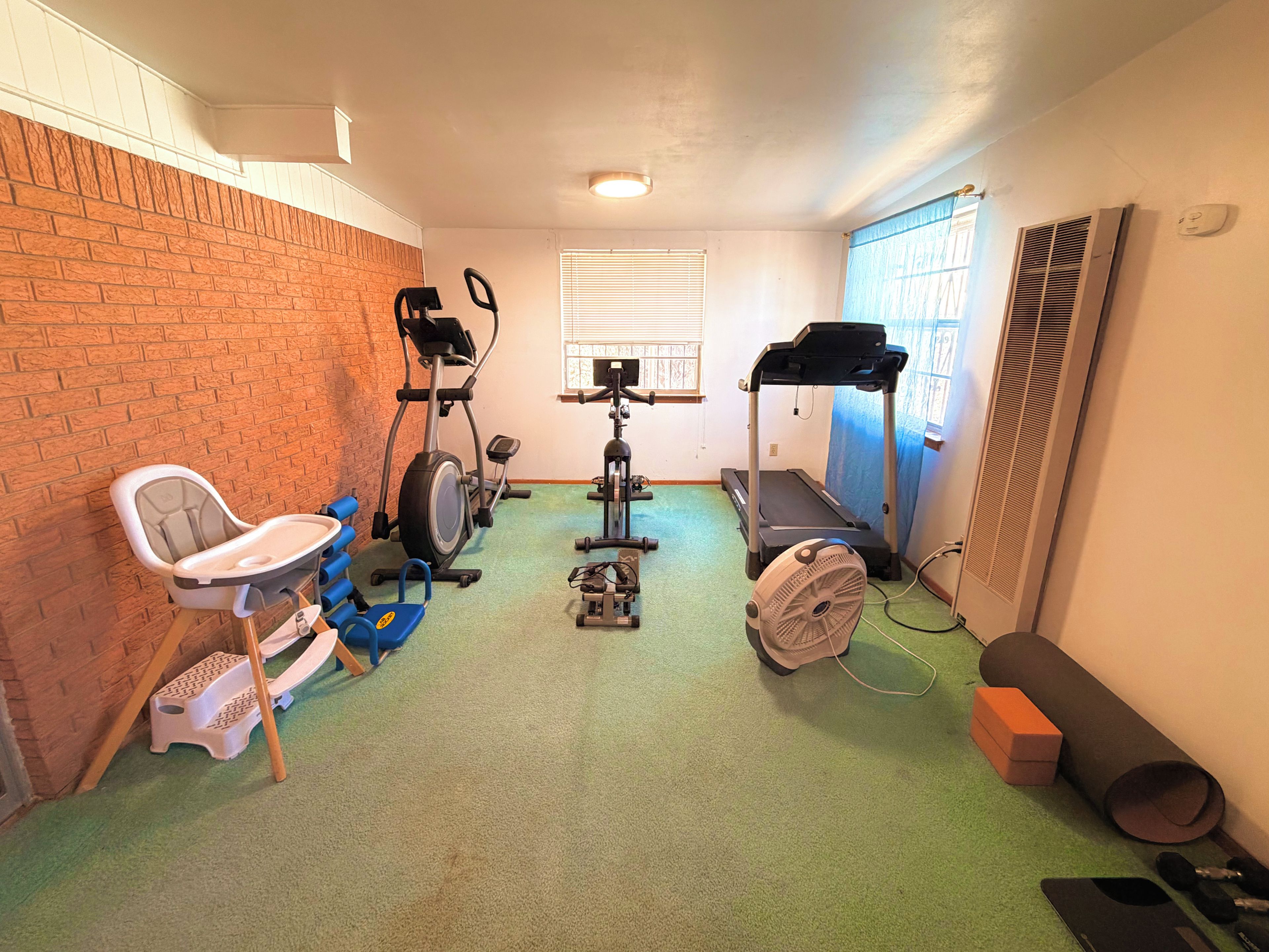 A home gym with exercise equipment including a treadmill, stationary bike, and weights.