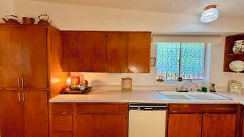 A kitchen with wooden cabinets, a dishwasher, a window with a view, and a light fixture.