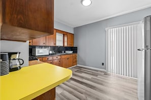 Cozinha compacta com armários de madeira, bancada amarela e porta branca.