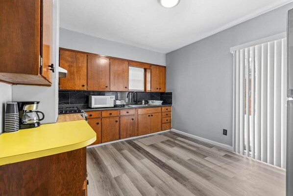 A compact kitchen with wooden cabinets, a microwave, and a coffee maker.