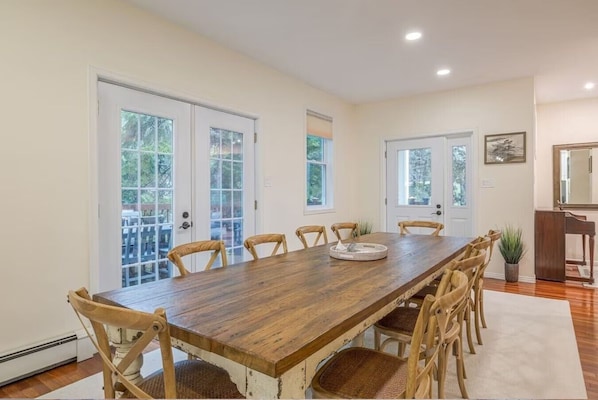 A dining room with a long wooden table, six chairs, and a small side table. - Steps to Acadia + Beach | Game Room | Sleeps 21 (Seal Harbor)