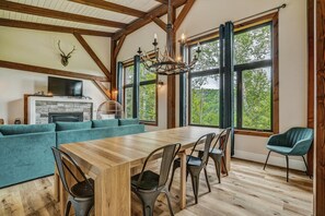 A spacious room with a wooden dining table, multiple chairs, a sofa, and a fireplace. - Luxury Chalet in Sainte-Béatrix / Spa & Sauna / Sleeps Up to 11 People, 1 Hour from Montreal (Sainte-Bã©Atrix)