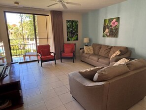 A living room with a sofa, chairs, a table, and a large window with a view of greenery. - The Resort Life- Pools, Beach Club, Gym, King Bed (Playas Del Coco)