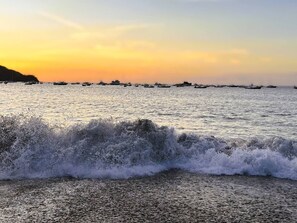 A beach scene with waves and boats in the distance. - The Resort Life- Pools, Beach Club, Gym, King Bed (Playas Del Coco)