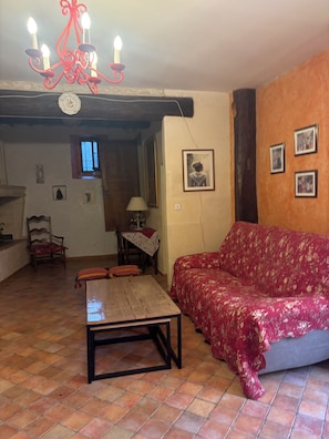 A living room with a red patterned sofa, a wooden coffee table, a chandelier, and a tiled floor. - Traditional Arles-style house at the foot of the Arènes, 3 bedrooms Air Conditioning (Arles)