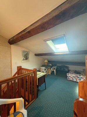 A room with a sloped ceiling, a skylight, a wooden staircase, a table with chairs, and a bed with a quilt. - Traditional Arles-style house at the foot of the Arènes, 3 bedrooms Air Conditioning (Arles)