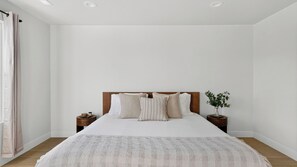 A bedroom with a bed, two bedside tables, a plant, and a window with curtains. - Lobo Silver Summit by Avantstay Mountain-view Balcony Game Room + Near Deer Valley (Park City)