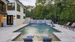 A rectangular swimming pool with a stone border, surrounded by a paved deck. - Take it to the Bank by Avantstay Lakefront + Pool + Spa Dock + Kayaks Elevator Access (Denver)