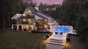 Une grande maison à plusieurs étages, dotée d’une piscine, d’un espace extérieur aménagé et d’une entrée bien éclairée.