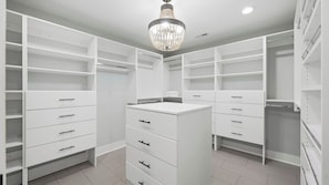 A walk-in closet with white shelving, drawers, and a central vanity with a mirror. - Take it to the Bank by Avantstay Lakefront + Pool + Spa Dock + Kayaks Elevator Access (Denver)
