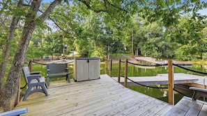 A wooden deck with a bench and a storage unit, overlooking a calm body of water with dock access. - Take it to the Bank by Avantstay Lakefront + Pool + Spa Dock + Kayaks Elevator Access (Denver)