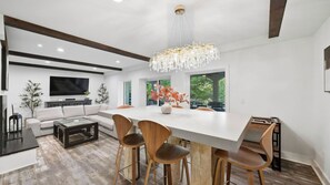 A modern kitchen with a large island, wooden chairs, and a chandelier. - Take it to the Bank by Avantstay Lakefront + Pool + Spa Dock + Kayaks Elevator Access (Denver)