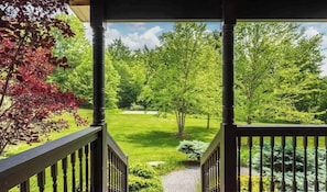 A covered outdoor area with a view of a well-maintained garden and trees. - Stoneline Chalet - Hot Tub, Sauna, Fire Pit, Game Rm (Jewett)