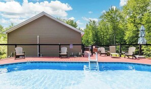 A swimming pool with a wooden deck, lounge chairs, and a covered seating area. - Stoneline Chalet - Hot Tub, Sauna, Fire Pit, Game Rm (Jewett)