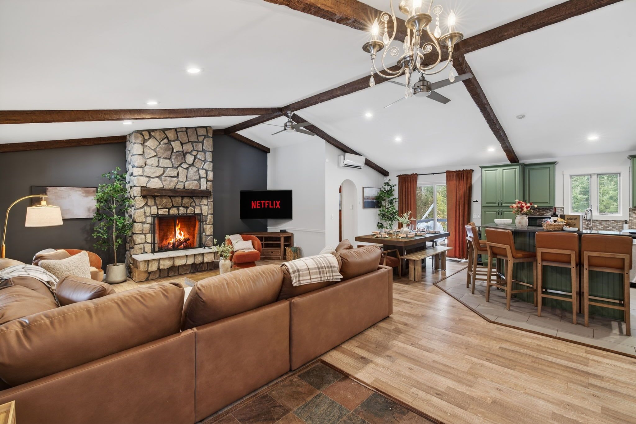 A modern living room with a stone fireplace, leather sofa, and a dining area with wooden chairs.