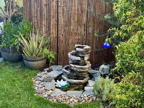 A garden with a stone water feature surrounded by rocks and plants. - Sunlit Oasis: Walk to Bay & Beach - Hot Tub, Fire Pit, BBQ & Wraparound Deck (San Diego)