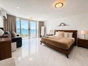 A modern hotel room with a large bed, a desk, a chair, and a view of the sea. - The best view in Isla Verde (Carolina)