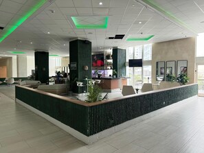 A modern reception area with a green accent wall, a bar, and seating arrangements. - Elegant Beach Escape with Ocean Views Isla Verde (Carolina)
