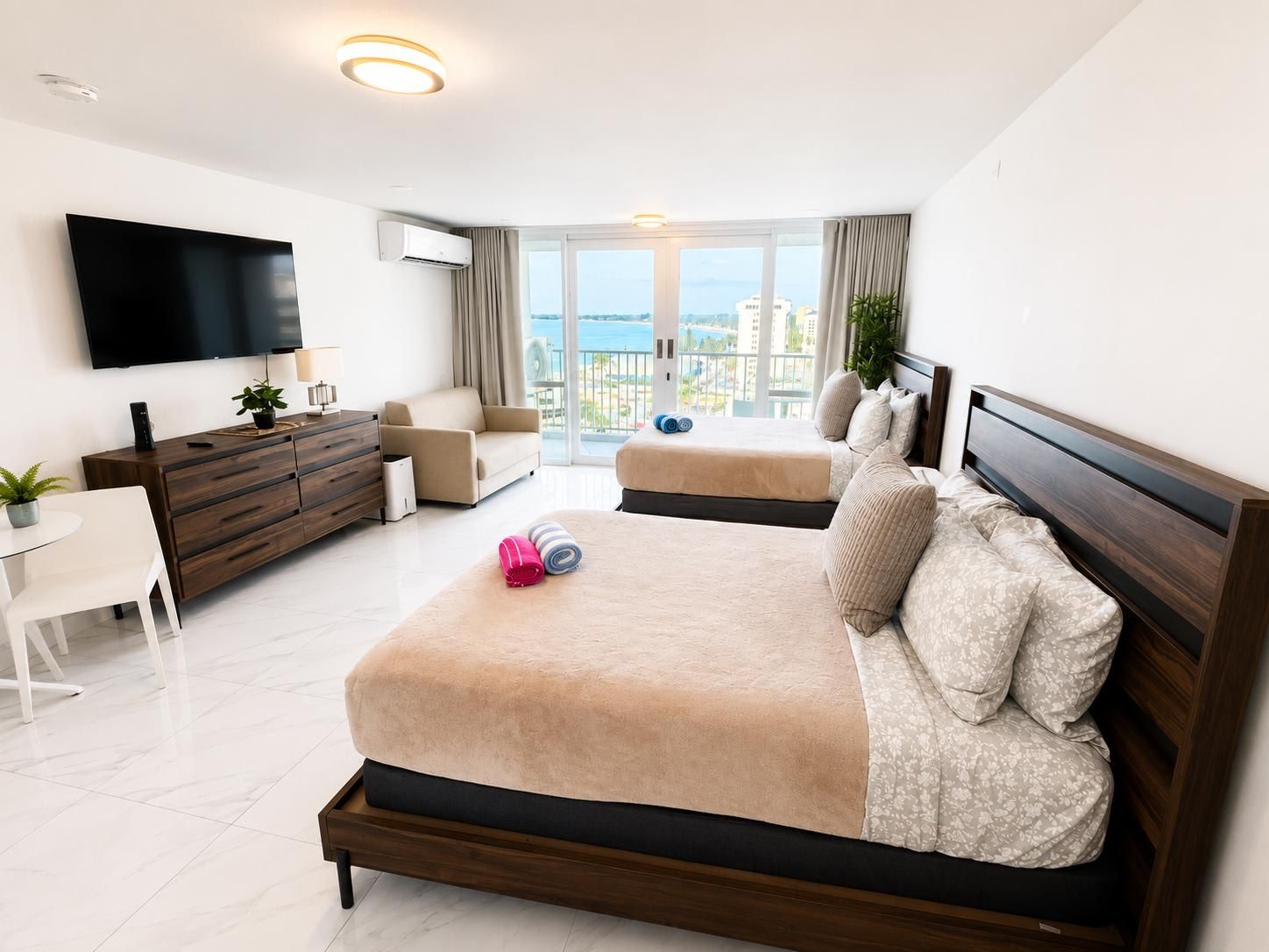 A hotel room with a bed, a TV, a desk, and a balcony with a view.