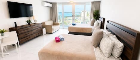 A hotel room with a bed, a TV, a desk, and a balcony with a view.