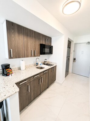 Una cucina moderna con mobili in legno, un lavello in acciaio inossidabile e un forno a microonde integrato.