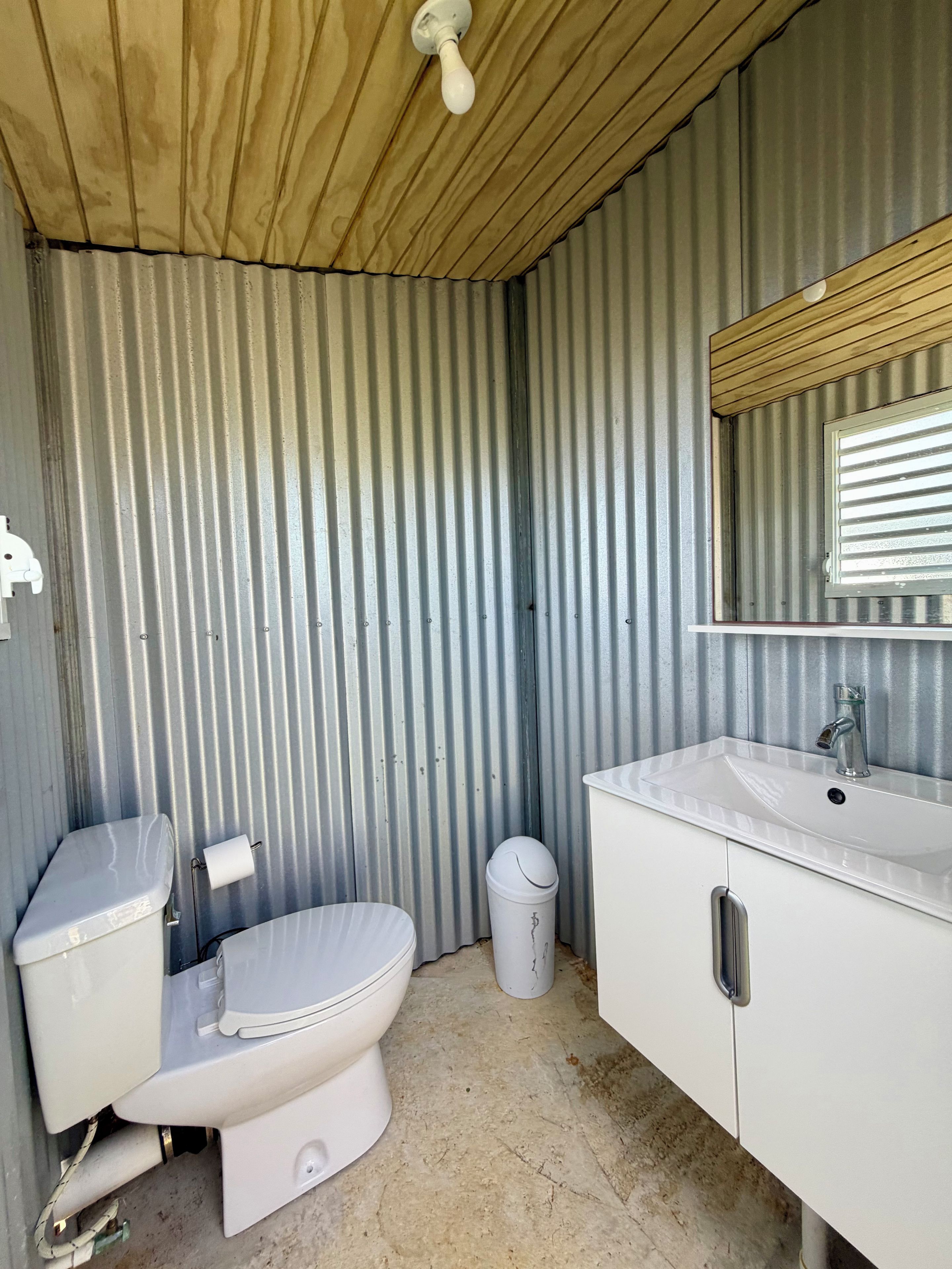 Une petite salle de bain comprenant des toilettes, un lavabo et un miroir.