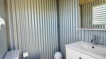 Une petite salle de bain comprenant des toilettes, un lavabo et un miroir.
