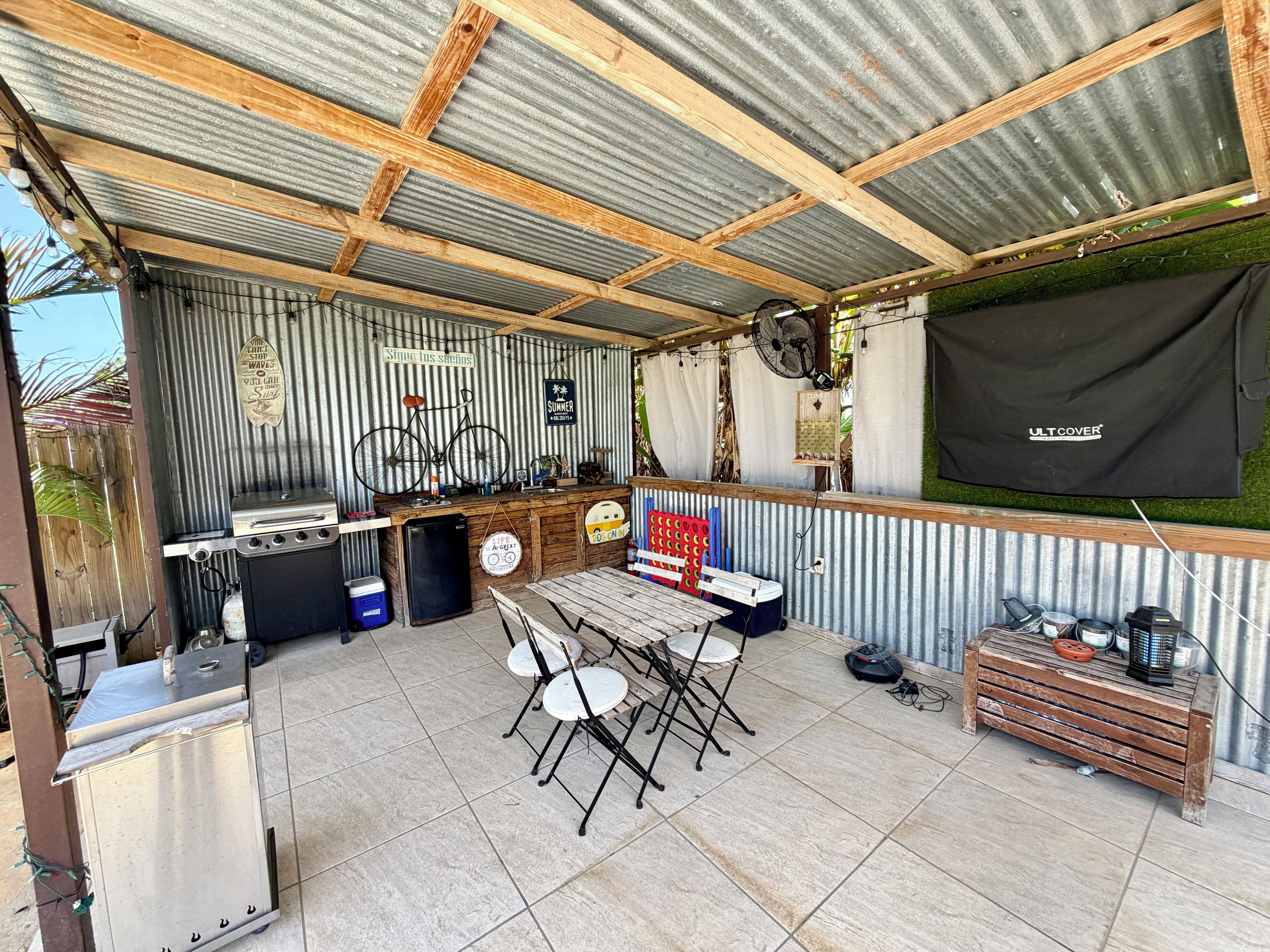 Un espacio al aire libre cubierto con una parrilla, asientos y un ventilador.