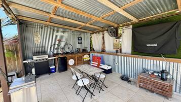 Un espacio al aire libre cubierto con una parrilla, asientos y un ventilador.