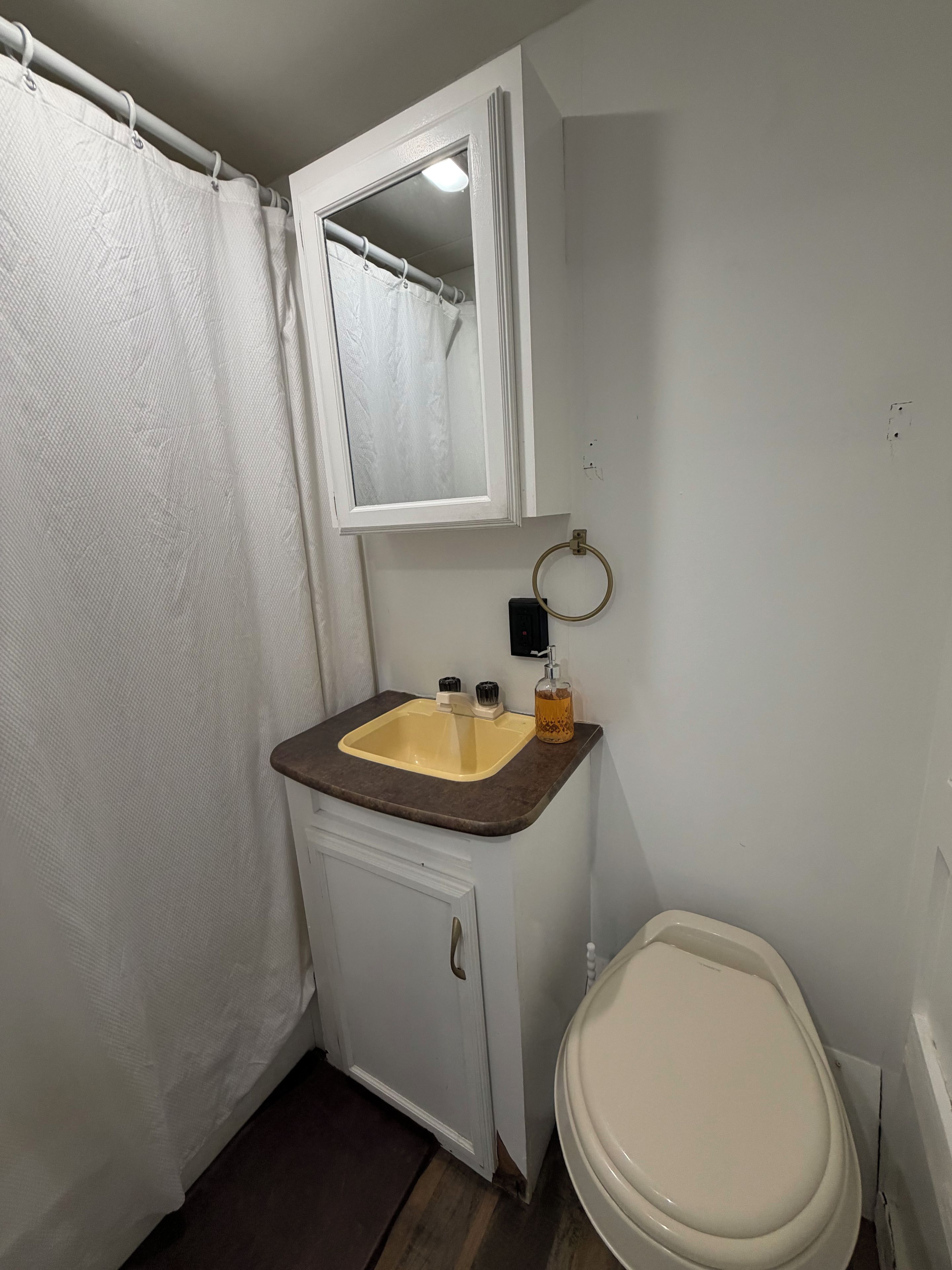 Un baño con inodoro blanco, lavamanos con espejo y cortina de ducha.