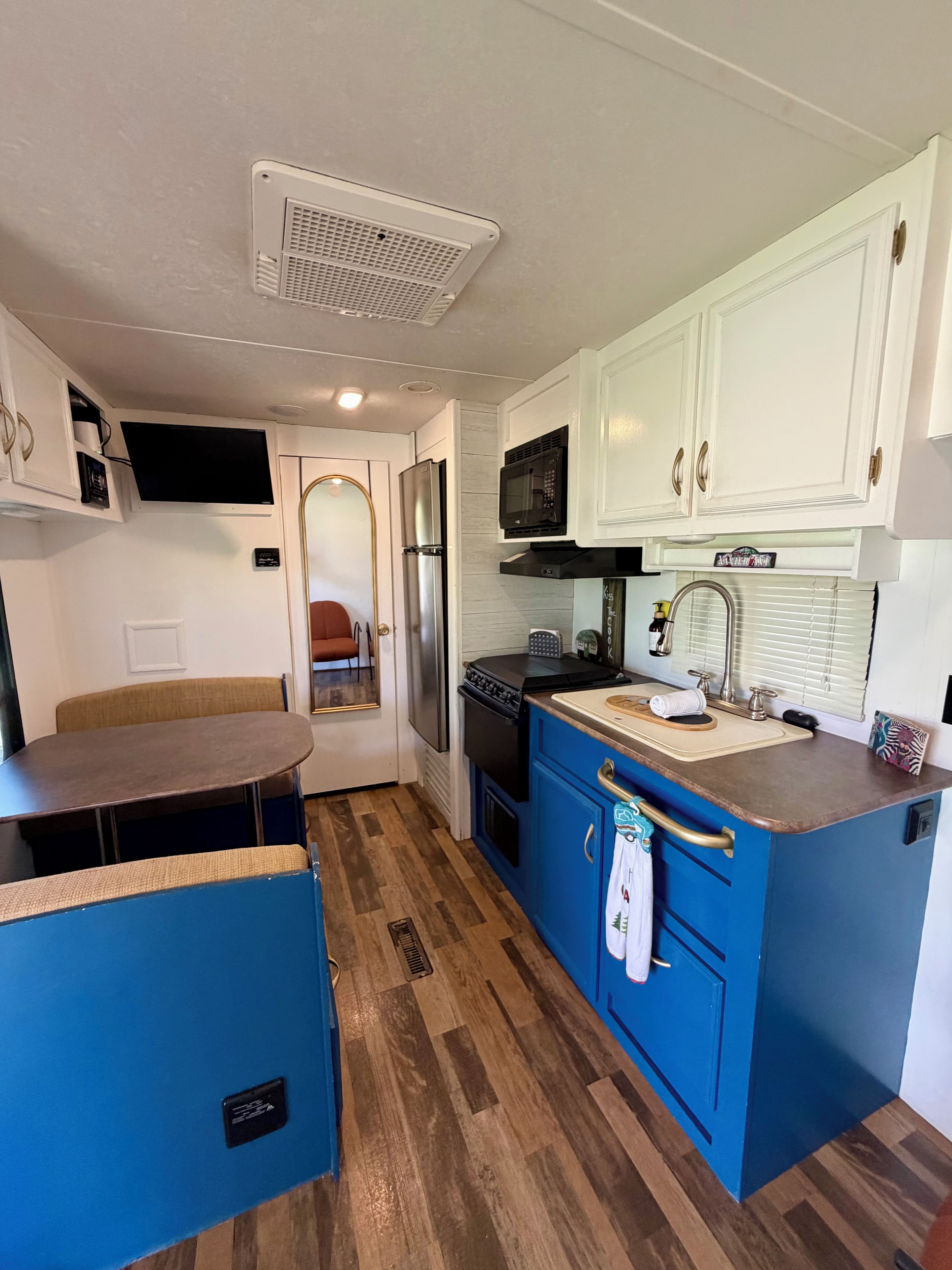 A compact kitchen with white cabinets, a microwave, a refrigerator, and a sink.