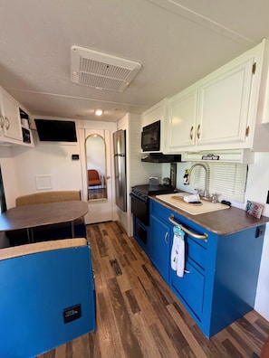 A compact kitchen with white cabinets, a microwave, a refrigerator, and a sink.