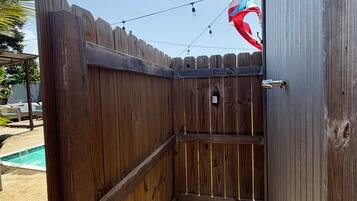 A wooden fenced area with a pool in the background.