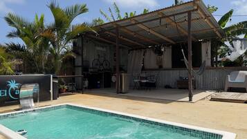 Un espace piscine doté d’un coin salon couvert, d’un barbecue et d’un panneau indiquant « El Ca. ».