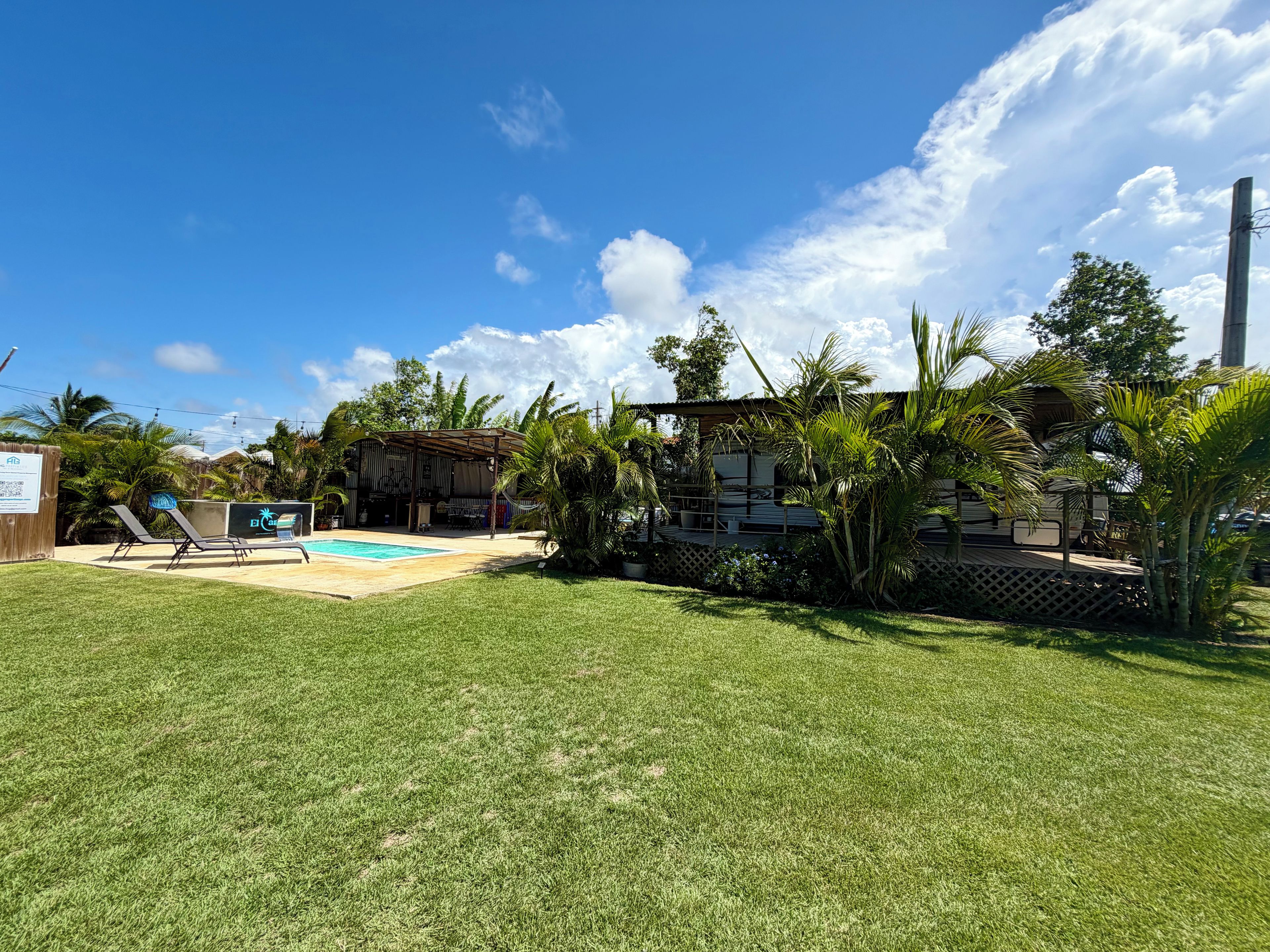 Um quintal com piscina, cadeiras de sol e uma área de varanda coberta.