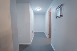 A narrow hallway with a light blue carpet, white walls, and a ceiling light. - 2336C - Ground 2B1B Unit with Laundry TV near UCB (Berkeley)