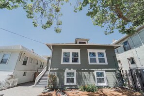 A two-story house with a front porch, a small garden, and a clear blue sky. - 2336C - Ground 2B1B Unit with Laundry TV near UCB (Berkeley)