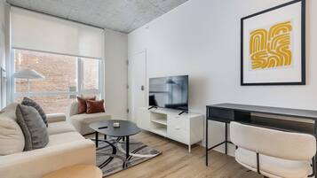 Uma sala de estar moderna com sofá, mesa de centro, televisão e escrivaninha com cadeira.