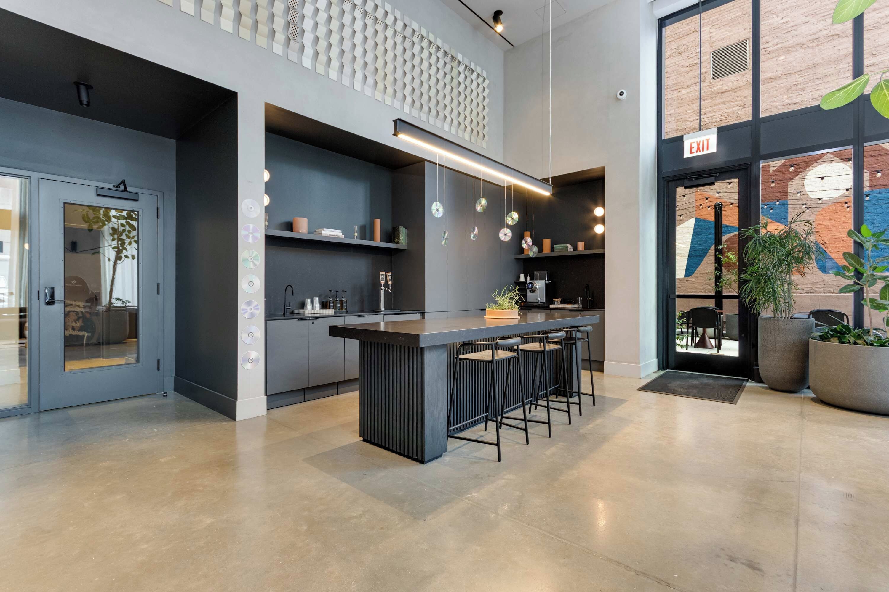Cozinha moderna com ilha central, banquetas e um mezanino com parede estampada.