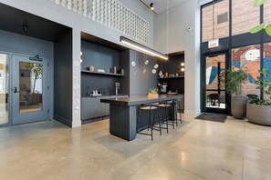 Cozinha moderna com ilha central, banquetas e um mezanino com parede estampada.
