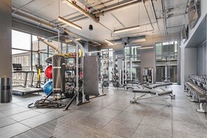 Uma academia com diversos equipamentos de exercício, incluindo esteiras, aparelhos de musculação e pesos livres.