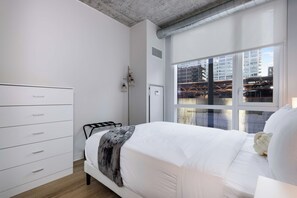 Quarto com cama, penteadeira, janela e vista para a cidade, além de radiador.