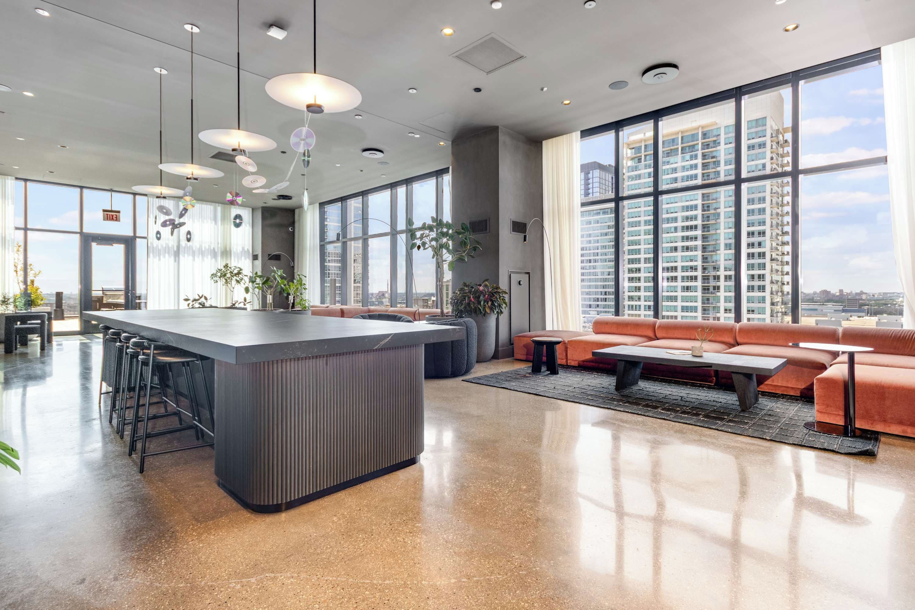 Decoração moderna com área de bar central, assentos e grandes janelas com vista para a cidade.