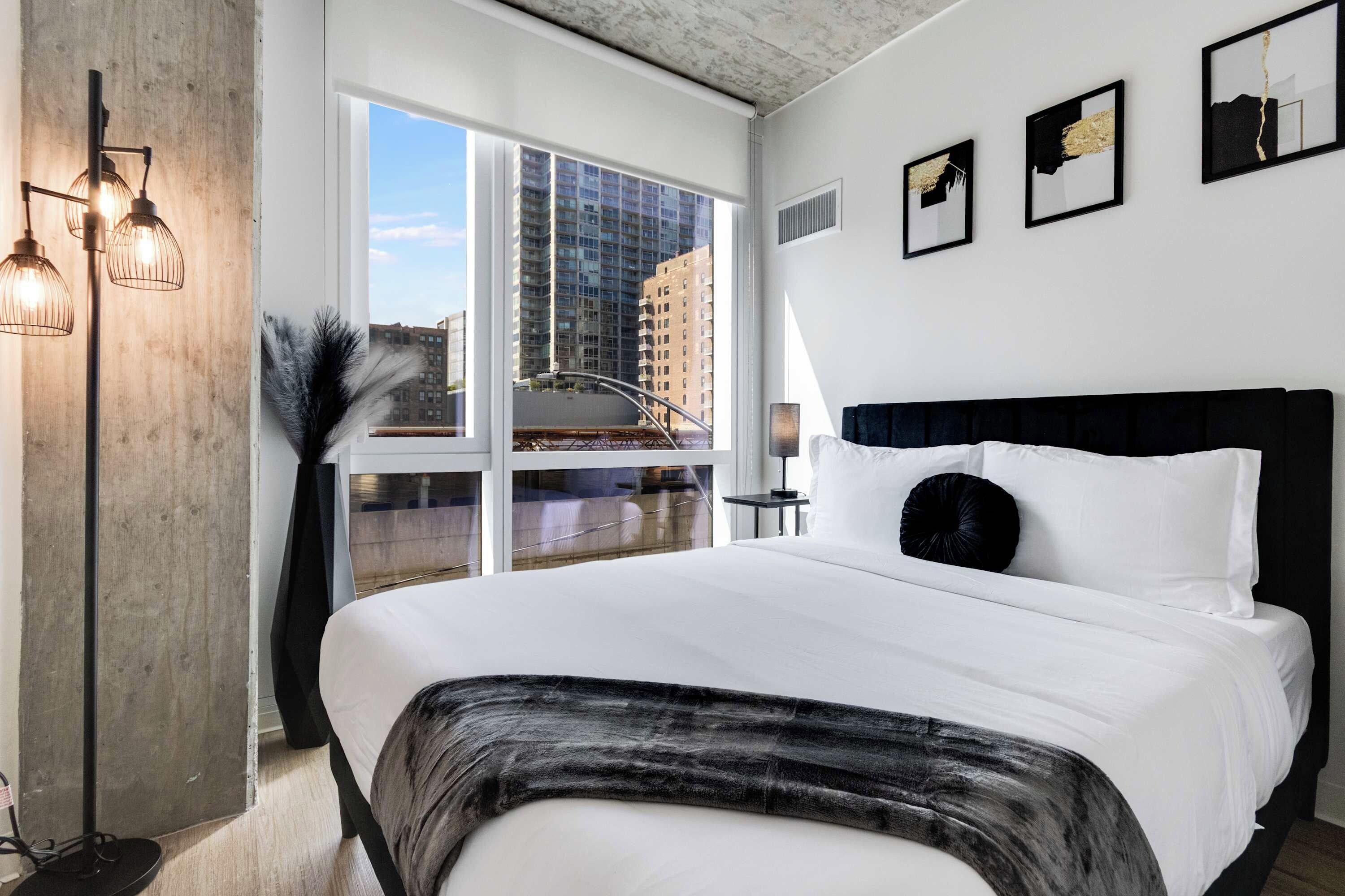Quarto de hotel moderno com uma cama grande, vista para a cidade e decoração minimalista.