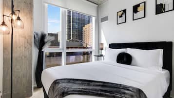 Quarto de hotel moderno com uma cama grande, vista para a cidade e decoração minimalista.